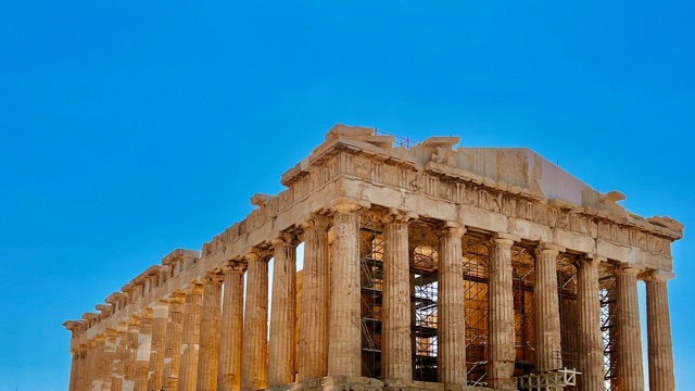 The ancient columns and pediment of the Parthenon stand against a clear blue sky