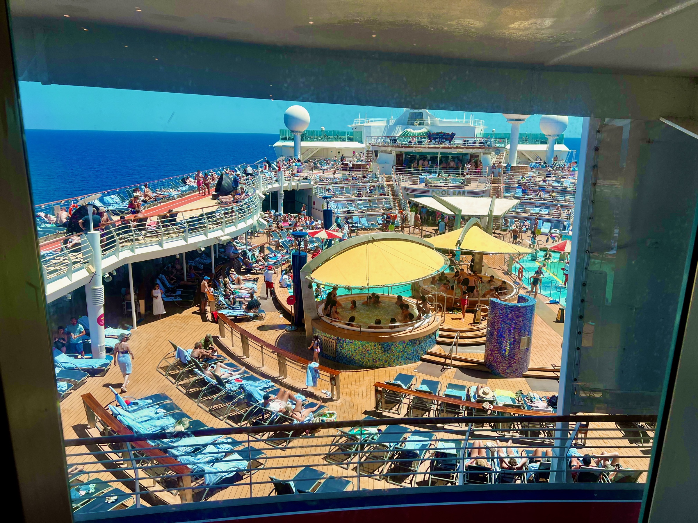The busy pool deck aboard Explorer of the Seas surrounded by blue water