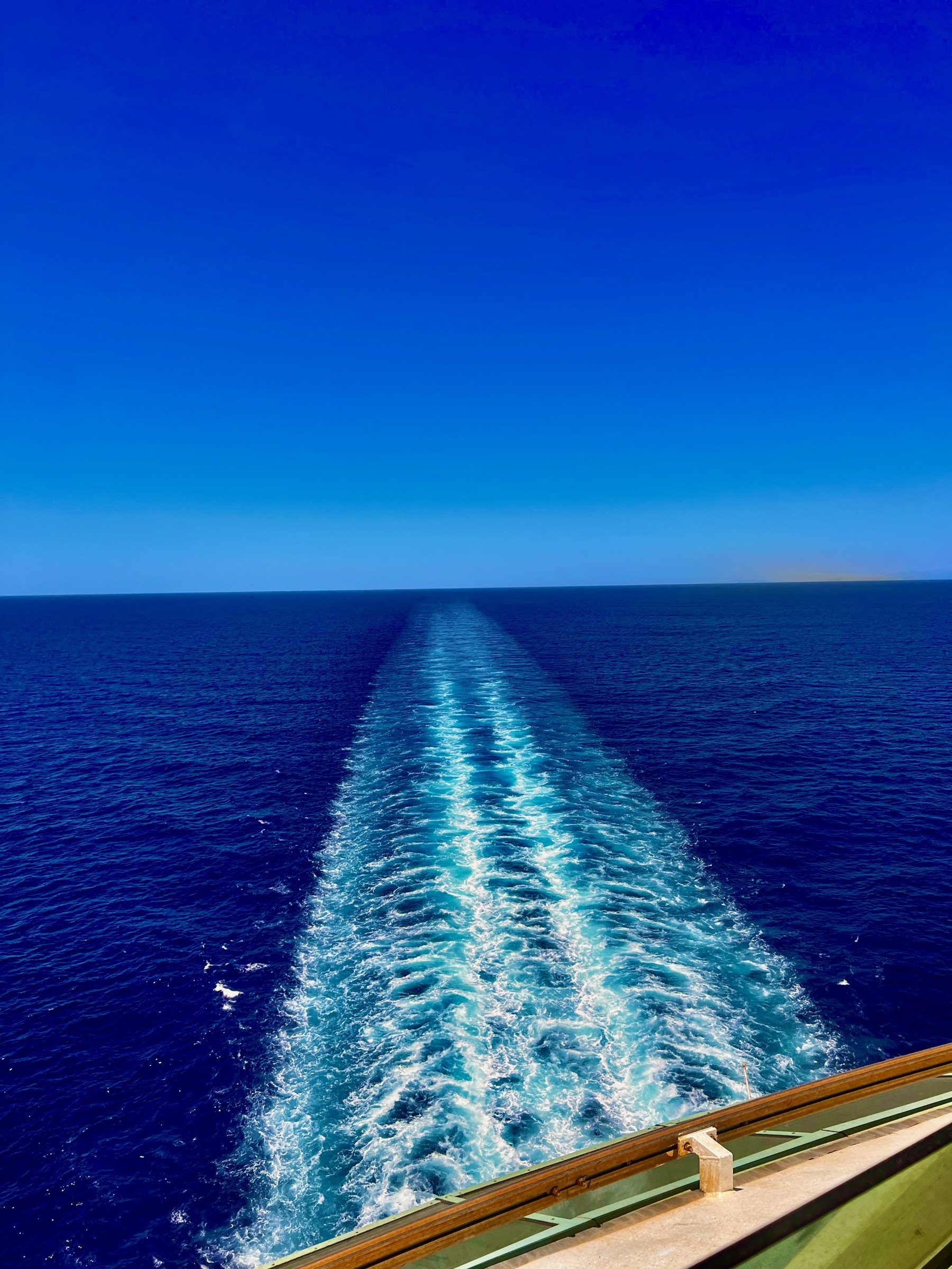 The bright white wake of Explorer of the Seas stretching across deep-blue water