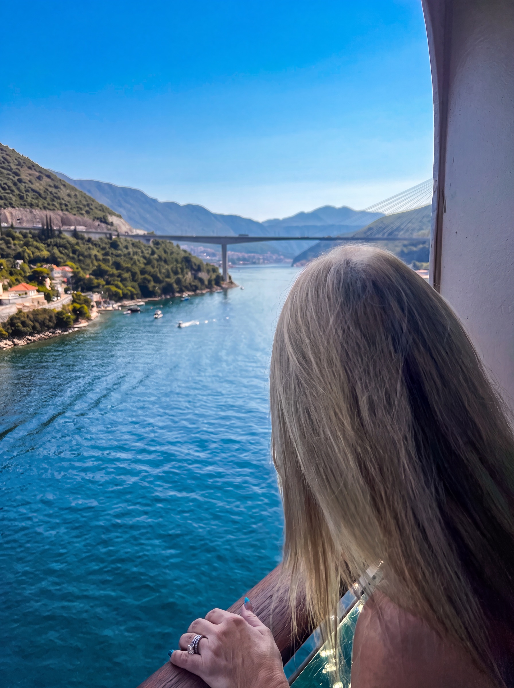 Dianne watching Dubrovnik's harbor and mountain-lined coast from the ship