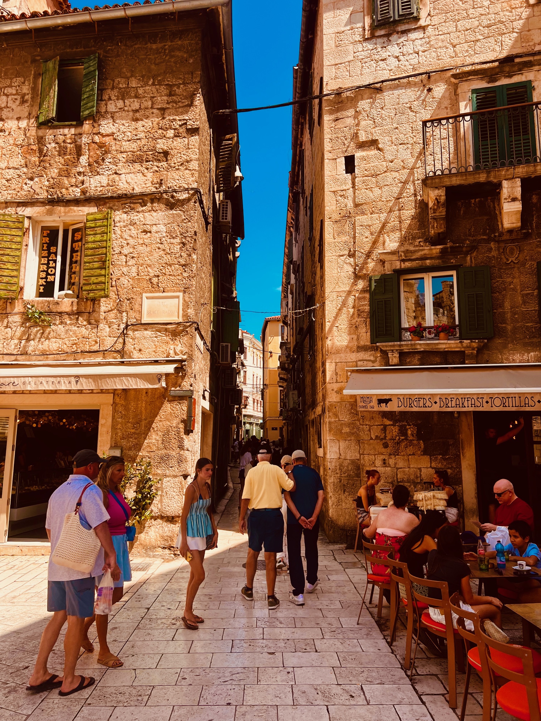 Visitors walking through a narrow stone lane in Split's Old Town