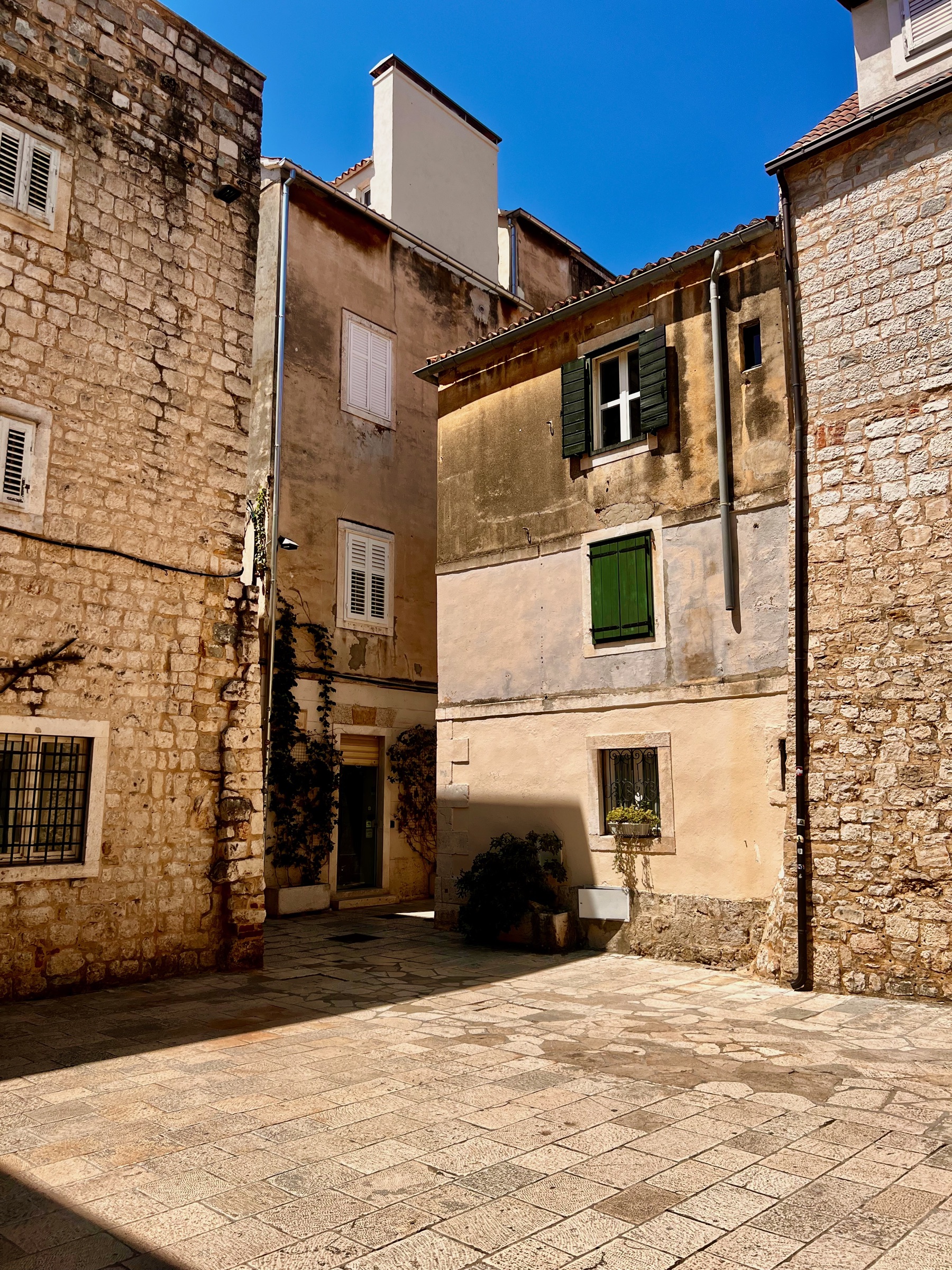 A quiet stone courtyard with green shutters in Split's historic center