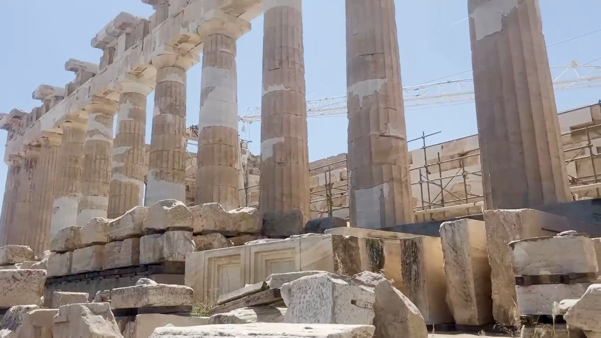 Parthenon columns rising behind scattered carved marble blocks