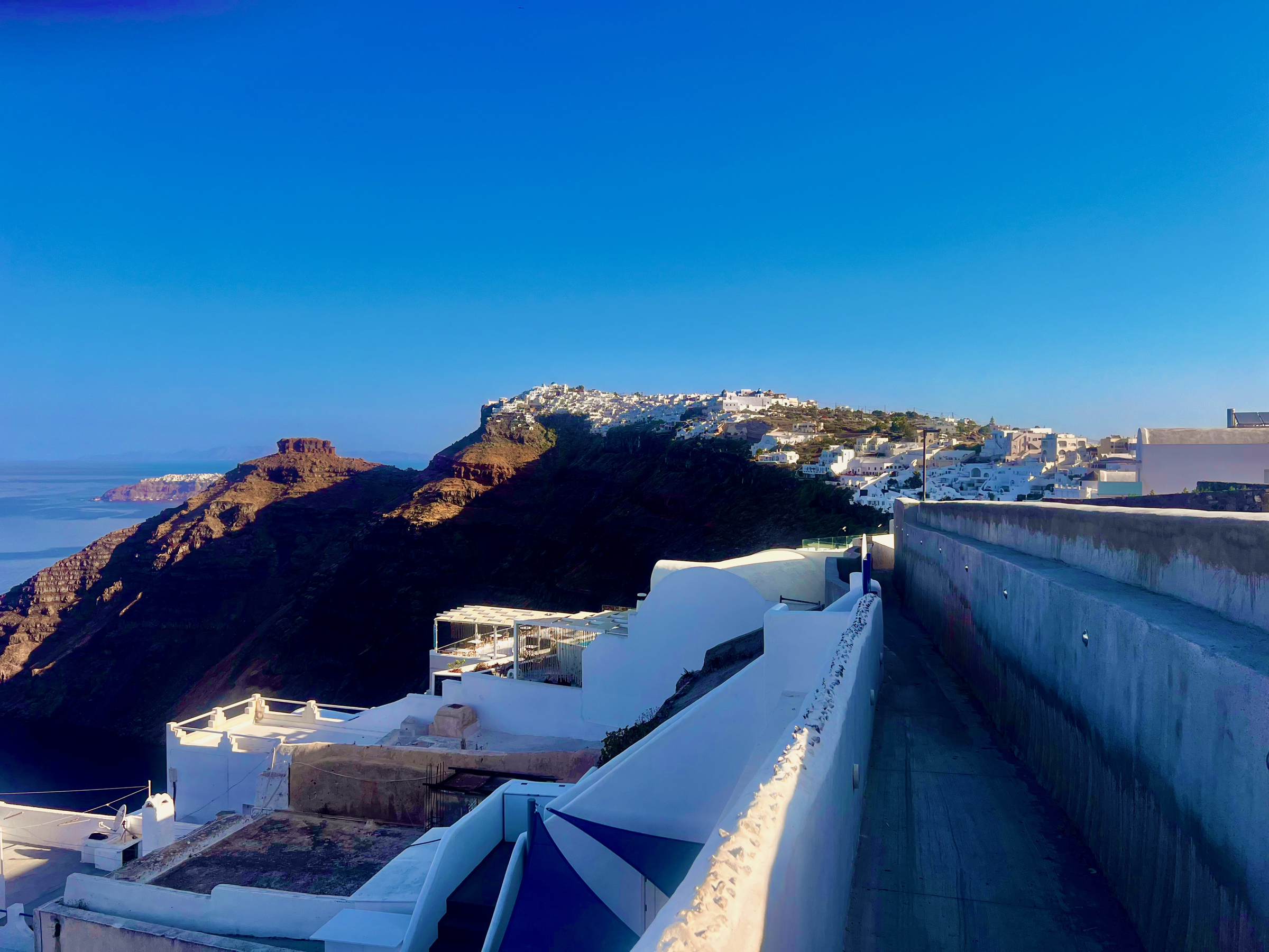 Whitewashed Santorini village stretching along a dark volcanic ridge