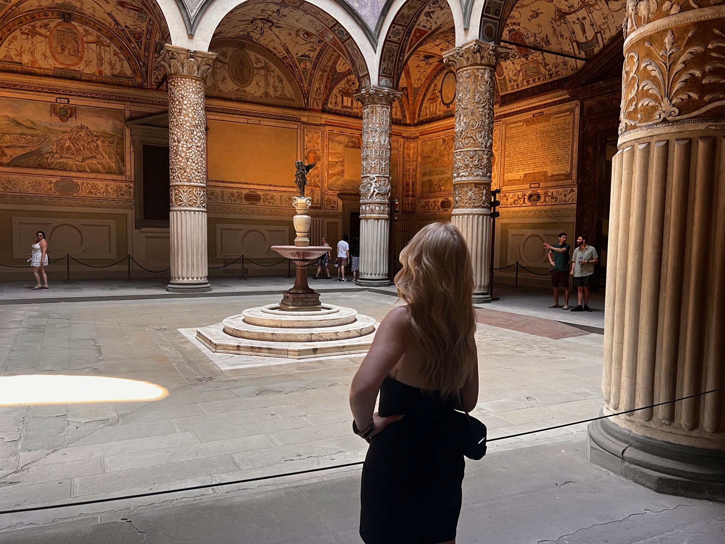 Dianne admiring an ornate Renaissance courtyard with painted walls and carved columns
