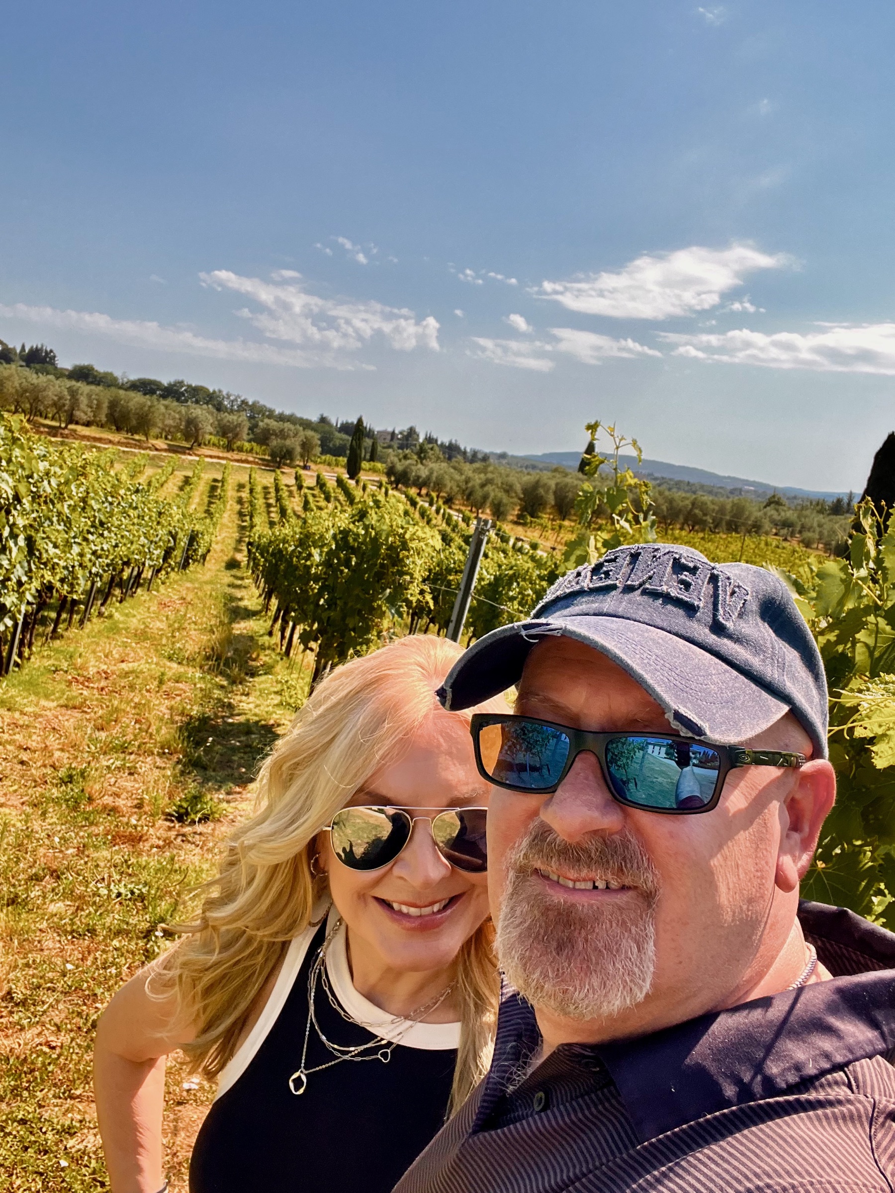 Dianne and Steve smiling together among rows of Tuscan grapevines