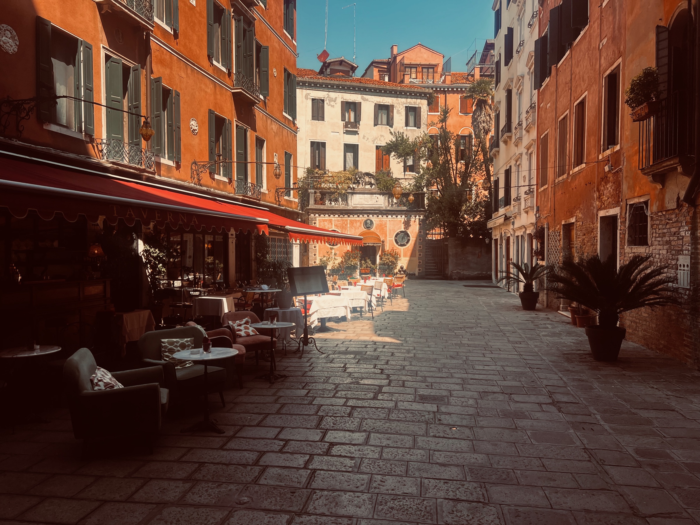 Tables arranged beneath warm lights in a quiet Venetian courtyard
