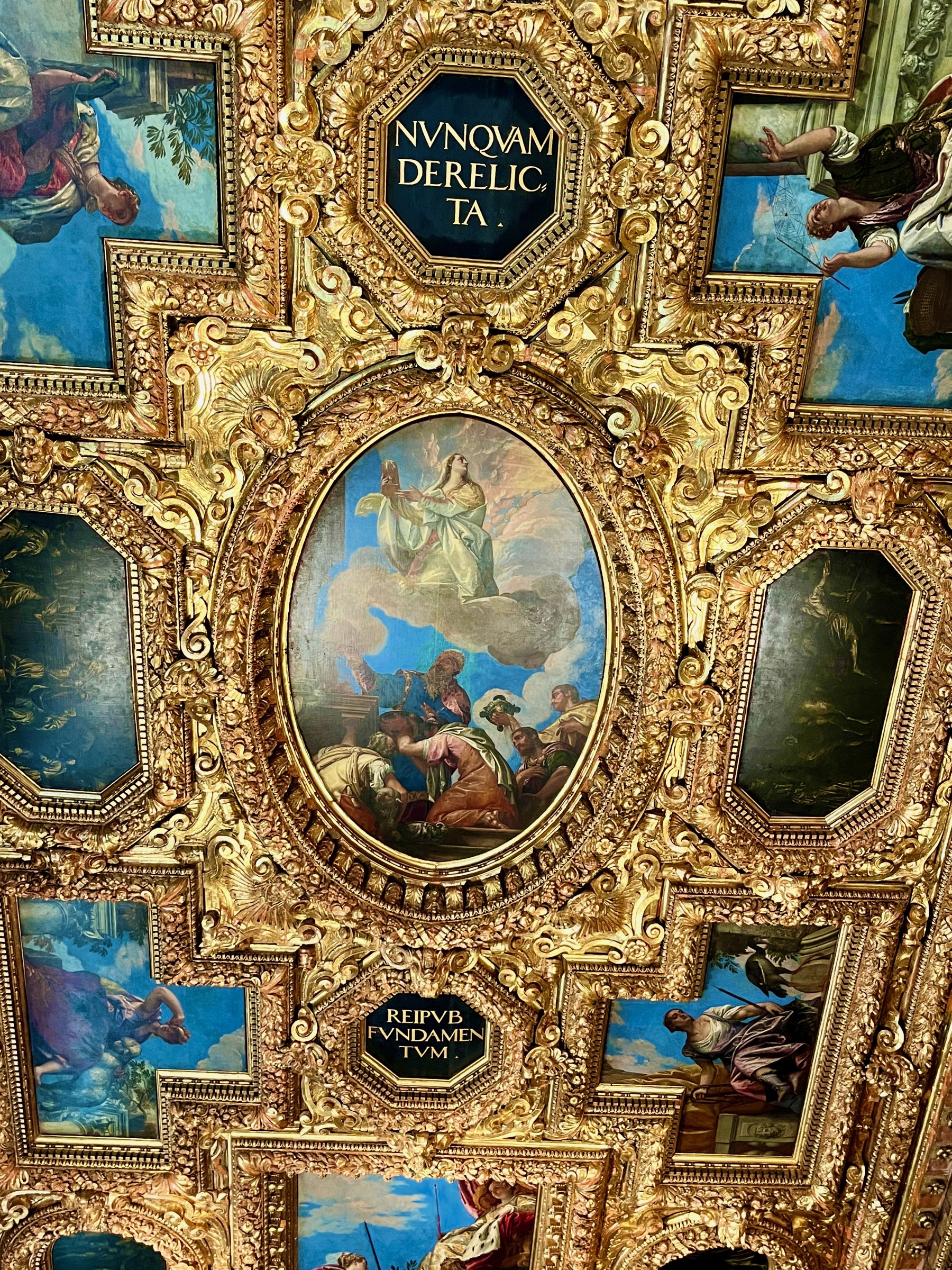 Ornate gilded ceiling filled with painted panels and carved details