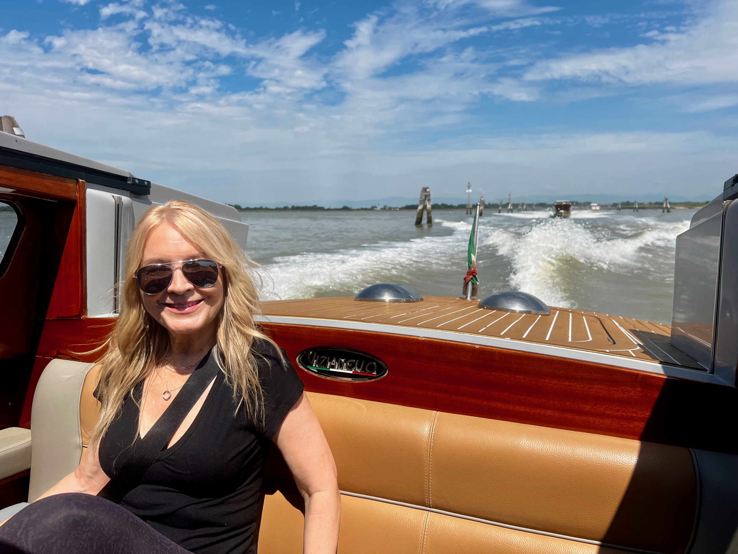 Dianne seated inside a private water taxi crossing the Venetian lagoon
